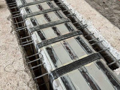 Blick von oben auf die Schubverstärkungen, die den Unterzug durch Durchbrüche umfassen. Dank Hochdruckwasserstrahlen blieb die verhandene Bewehrung erhalten.